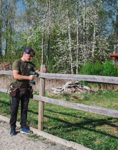 En handyman från Hus och Hemservice skruvar på ett staket till en paddock.